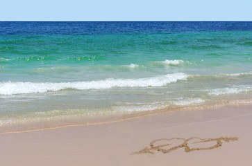 Two hearts with an arrow drawn on sand on beach - love concept