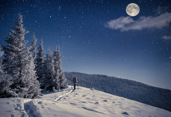 Travel in winter mountains at night with stars and a full moon