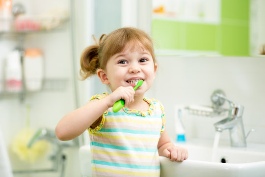 kid girl brushing teeth in bathroom
