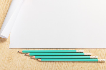 Scroll of paper with  pencils on a wooden surface.