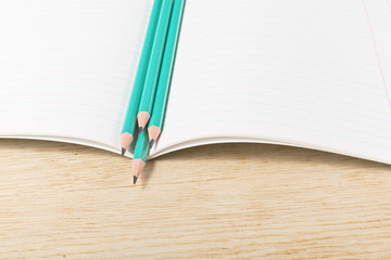 Notebook with pencils and on a wooden surface.