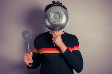 Young man hiding behind colander