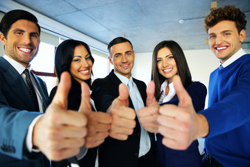 Portrait of happy young business people with thumbs up sign