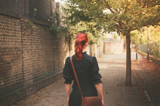 Young redhead woman walking in alley