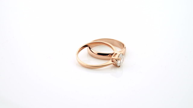 Wedding rings in rose gold turning slowly on white background