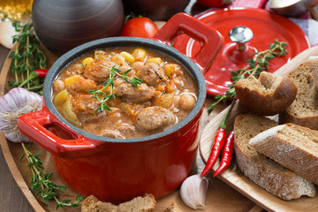 vegetable stew with sausages in a red pan