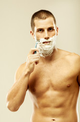 Young muscular man shaving