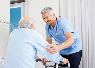 Caretaker Helping Senior Man To Use Walking Frame