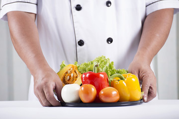 cook holds tray of vegetable