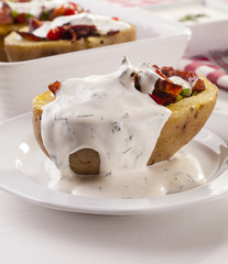 Baked potatoes stuffed with bacon served with dill sauce