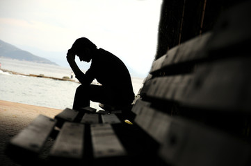 depressed young man sitting on the bench - obrazy, fototapety, plakaty