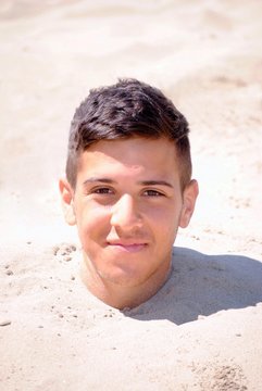 Ragazzo nella sabbia fino al collo