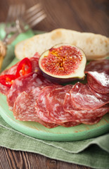 meat platter of Cured Meat and figs on green wooden board