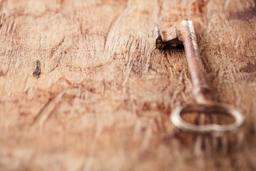 large rusty vintage metal key on old wooden background