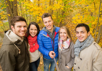 smiling friends taking selfie in autumn park