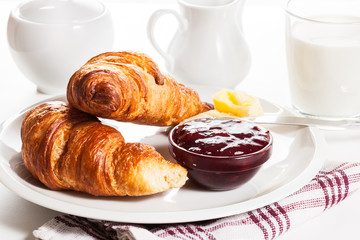 Fresh croissants with butter and a glass of milk
