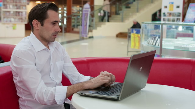 Man in despair and hesitant at work with a laptop