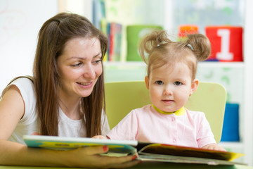 kid girl and mother read a book indoors