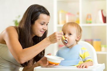 Obraz na płótnie Canvas Mom spoon feeds child