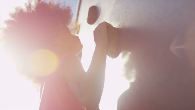 Pretty young girl climbing a boulder wall in a playground