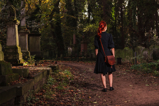 Young redhead woman standing in cemetery