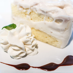 Coconut cream cake on a white plate with a bit of whipped cream