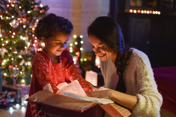 Lovely mother and her daugther opening a gift in front of the Ch
