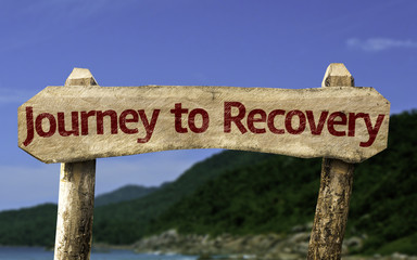 Journey to Recovery wooden sign with a beach on background