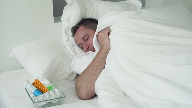 Sick, ill man lying in bed at home