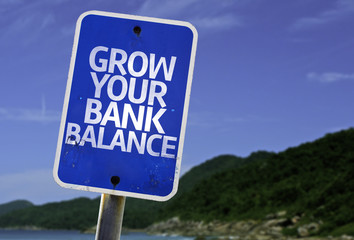 Grow Your Bank Balance sign with a beach on background