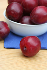 Fototapeta na wymiar prugne rosse su tavolo di legno_ frutta