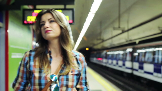 Beautiful hipster woman waiting for metro on platform station