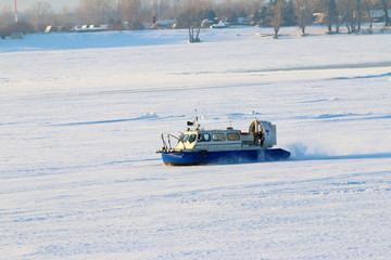 Hovercraft crossing frozen river in the sunny day