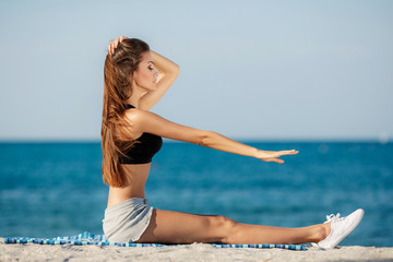 Fototapeta na wymiar The young woman moves training on a beach.
