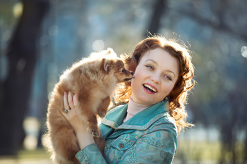 Pomeranian dog and  red haired woman playing outdoor