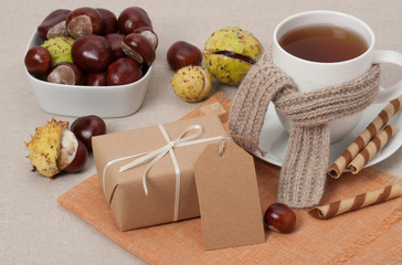 Obraz na płótnie Canvas Gift Box With Blank Tag. Cup Of Hot Tea With Sweets. Chestnuts.