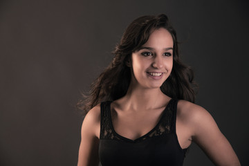 Naklejka premium Smiling cute brunette teenage girl wearing black dress. Studio f