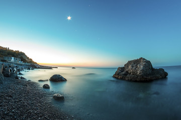 Sunrise on beach with rocks and sea