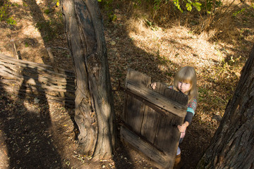 Young girl playing with an old wooden gate