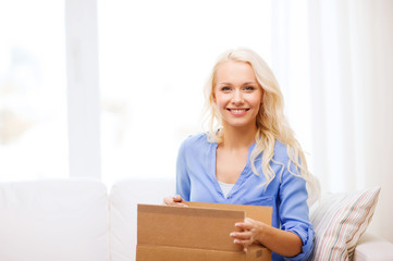 Fototapeta na wymiar smiling young woman opening cardboard box