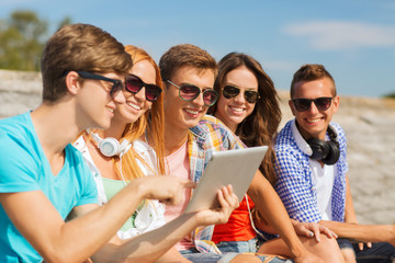 group of smiling friends with tablet pc outdoors