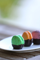 Colorful macaroons in plate on wooden table, close-up