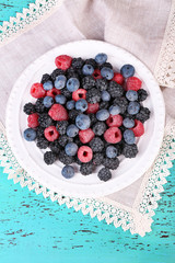 Iced berries on plate, on color wooden background