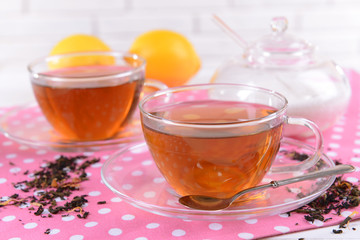 Cups of tea on table on brick wall background
