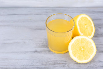 glass of juice with fresh lemon on grey wooden table