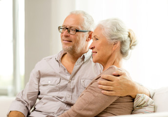 happy senior couple sitting on sofa at home