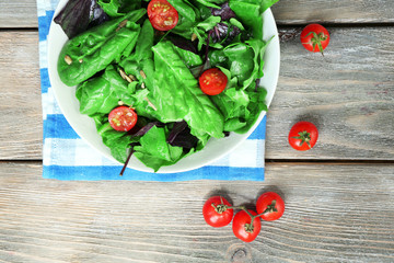 Fresh green salad in bowl on wooden table