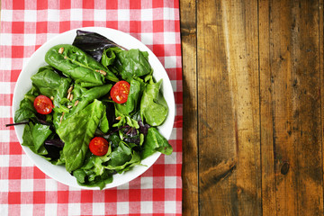 Fresh green salad in bowl on wooden table