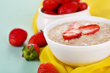 Tasty oatmeal with strawberry on table close-up