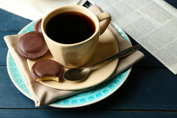 Cup of coffee with tasty cookies on color wooden background